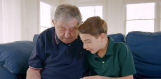 Elliot and Jack, a Holocaust survivor, sit together on the couch while going through an old photo album in "The Number on Great-Grandpa's Arm." The film will be shown on April 22. (Photo courtesy of HBO documentary films)