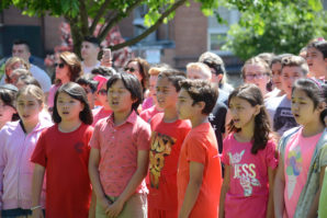 Students garbed in pink, maroon, and red sing as part of a ceremony for Zachary Portnoy's garden. (Photo by Janelle Clausen)