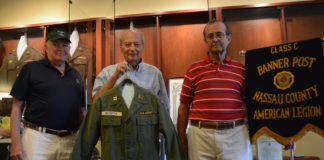 Anthony W. Buzzitta, flanked by two fellow veterans, holds up his old U.S. Army jacket. (Photo by Janelle Clausen)