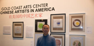 Shi Xiangdong standing in front of the his paintings stands in front of his work in the Gold Coast Art Center's new exhibit. (Photo by Demi Guo)