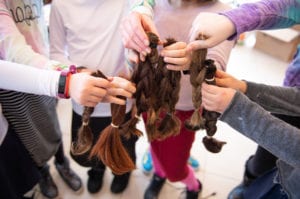 Donors hold samples of hair that will go toward creating wigs for children with cancer in Israel.  (Photo by Eli Schilowitz)