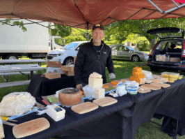 Brent Dilman, also known as Brent The Cheese Guy, poses at his stand which offers artisanal, organic, and kosher cheeses like parmesan, goat cheese, cheddar jalapeno, and much more at Deep Roots Farmers market.