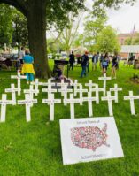 A tribute to the victims of the Uvalde school shooting. The tribute includes 21 white crosses with the names of the 19 children and 2 teachers that were killed, and a poster with a photo of the U.S. and all victims of school shootings with the caption, "The United States of School Shootings."