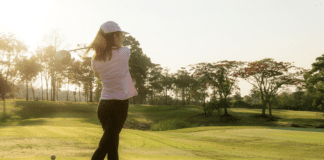 A woman golfer mid swing on a golf course.